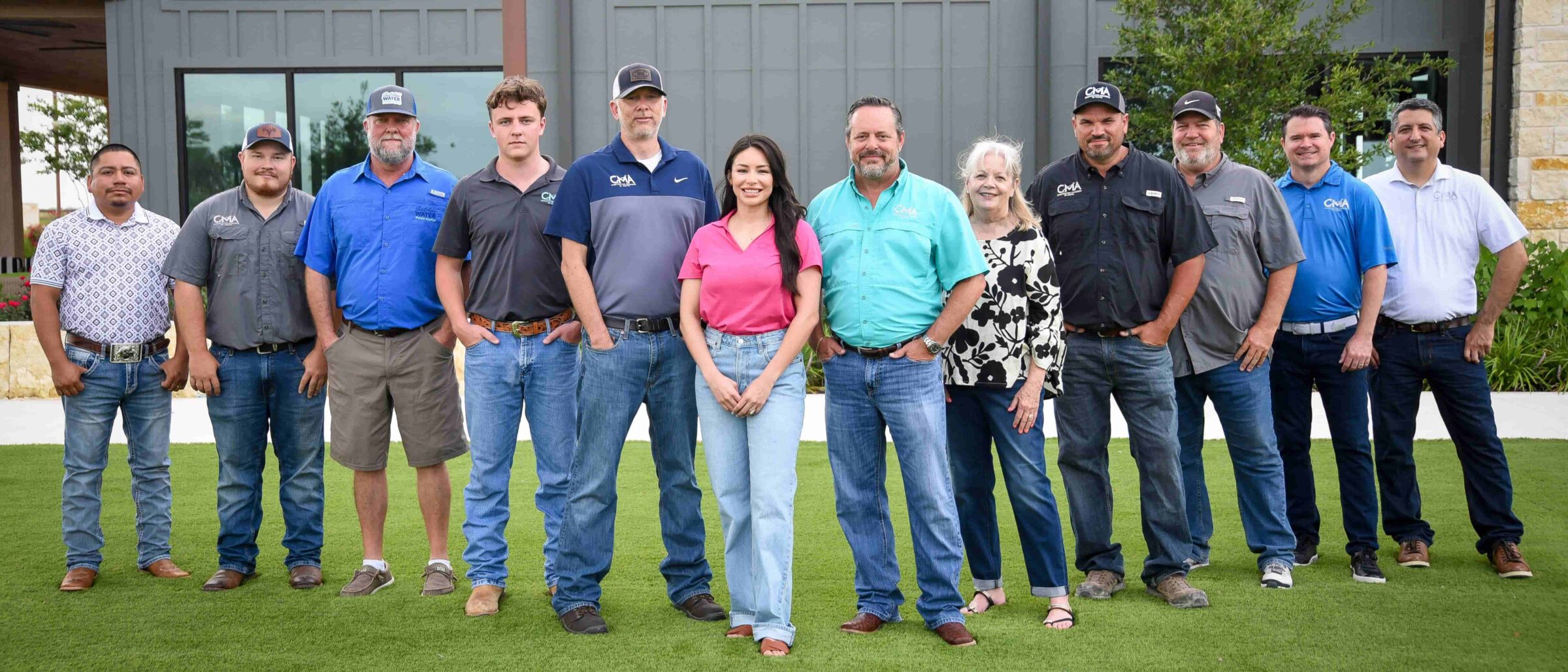 The CMA of Austin team and trade partners standing together outside a completed amenity center clubhouse project.