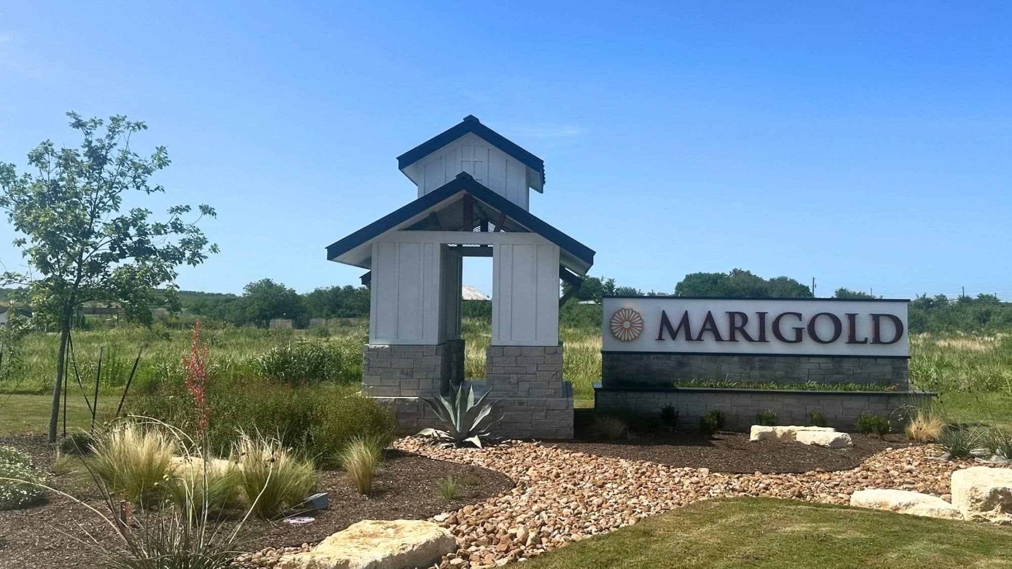 Marigold community, by D.R. Horton, entrance monument in Kyle, Texas, with a white tower, limestone base, and sign wall