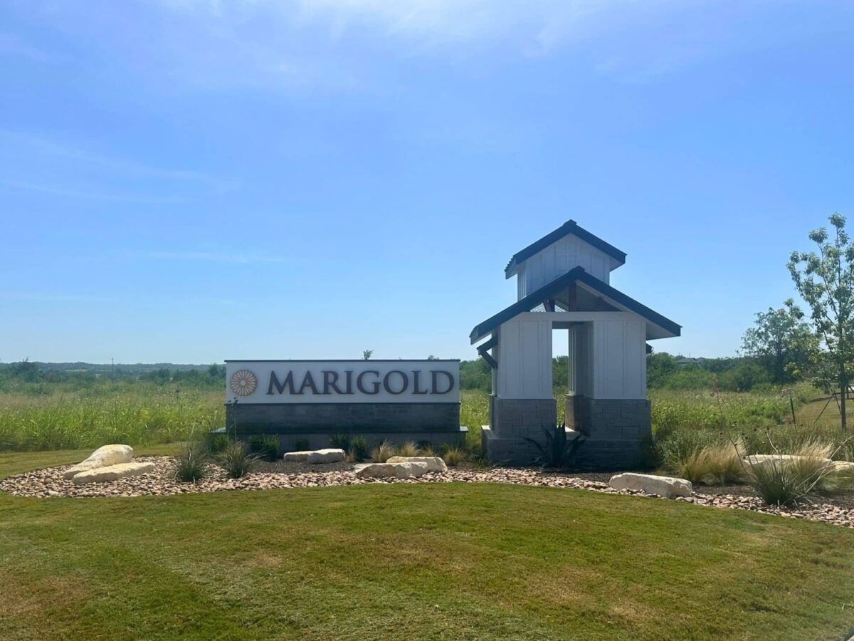 Marigold community entrance monument in Kyle, Texas, with a white tower, limestone base, and sign wall