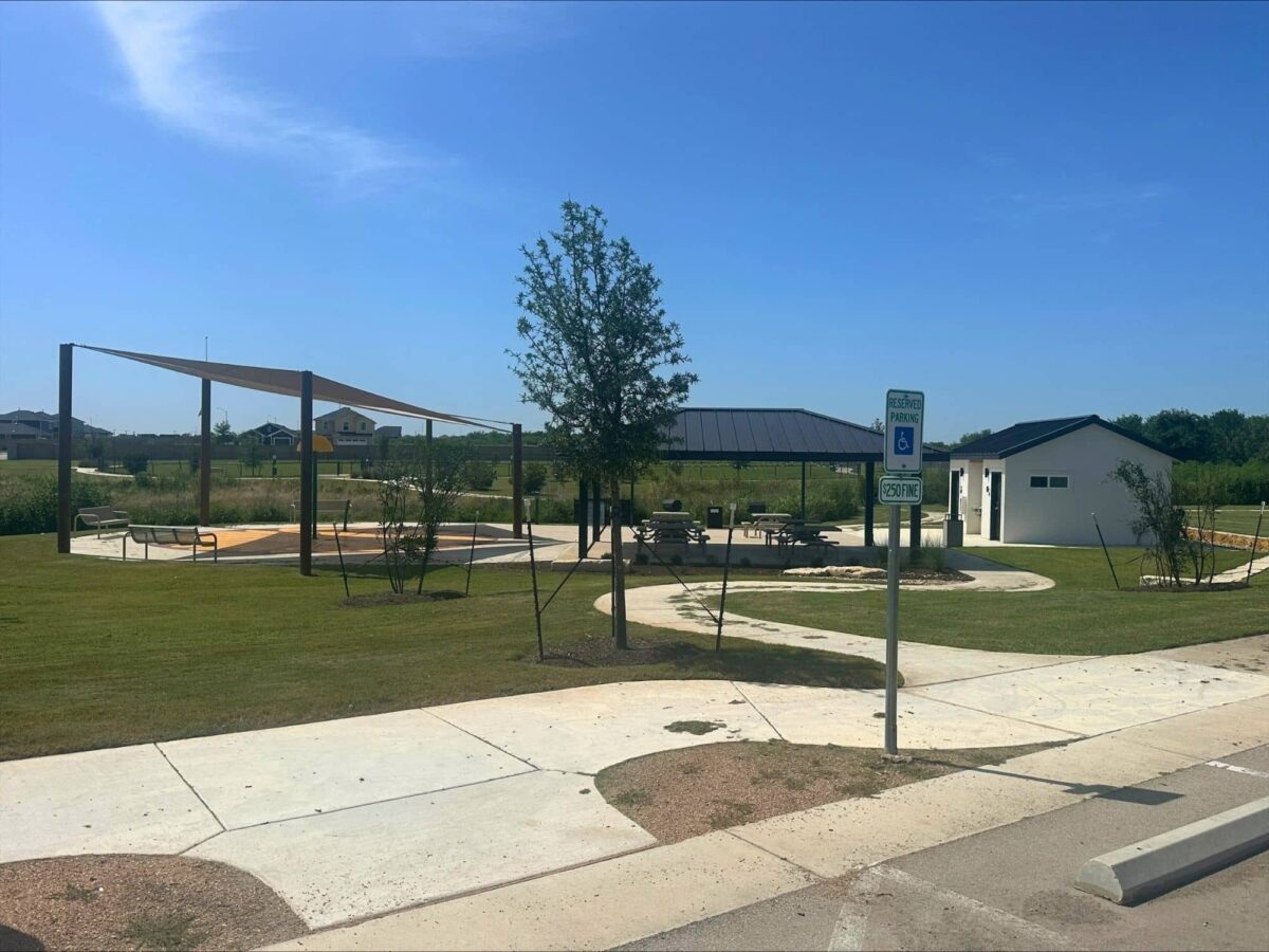 Covered pavilion, shaded splash pad, and restroom building at the Marigold amenity park in Kyle, Texas.